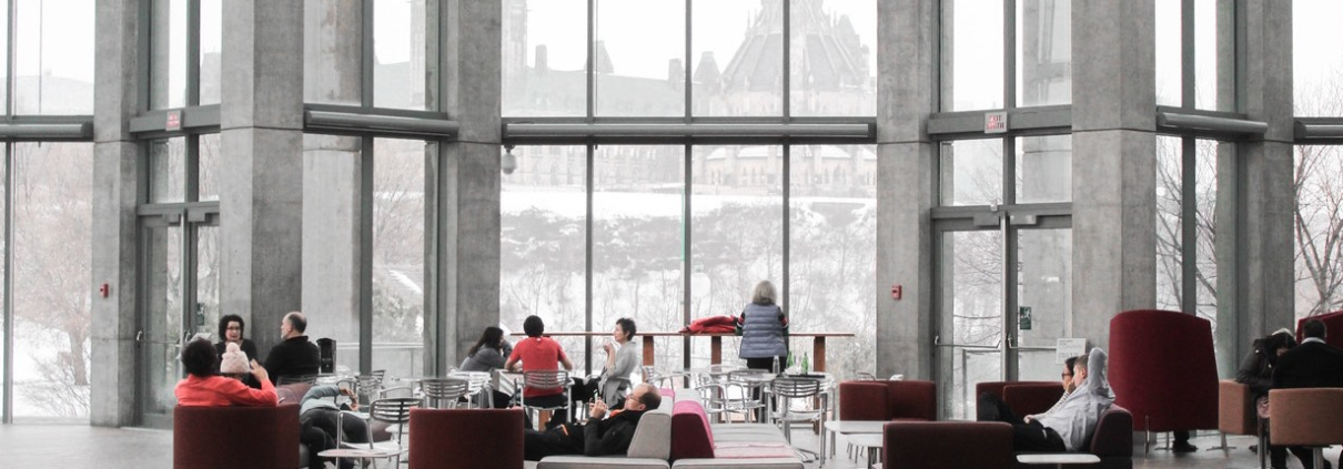 People resting on chairs within an open indoor space reminiscent of a library