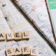 A phone disaplying a health passport app and QR code beside Scrabble letters spelling the words 'Travel Safe'