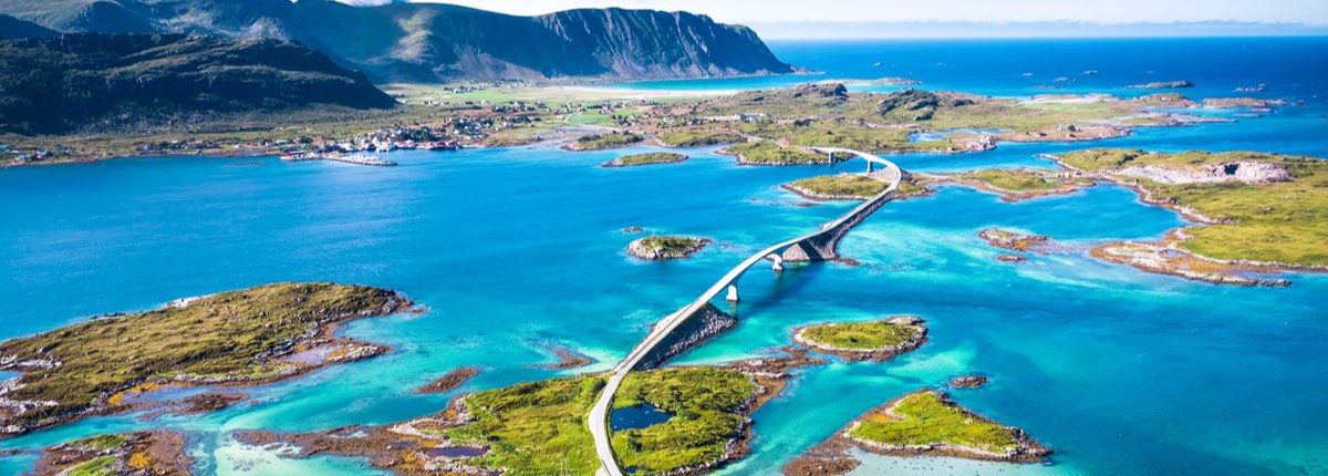 An aerial shot of a road bridge connecting several small islands with a larger, mountainous island in the background