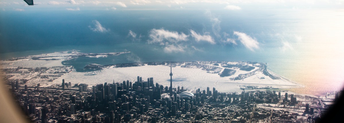 An aerial view of downtown Toronto, featuring the CN Tower and SkyDome against a backdrop of a frozen inner harbour beside Lake Ontario