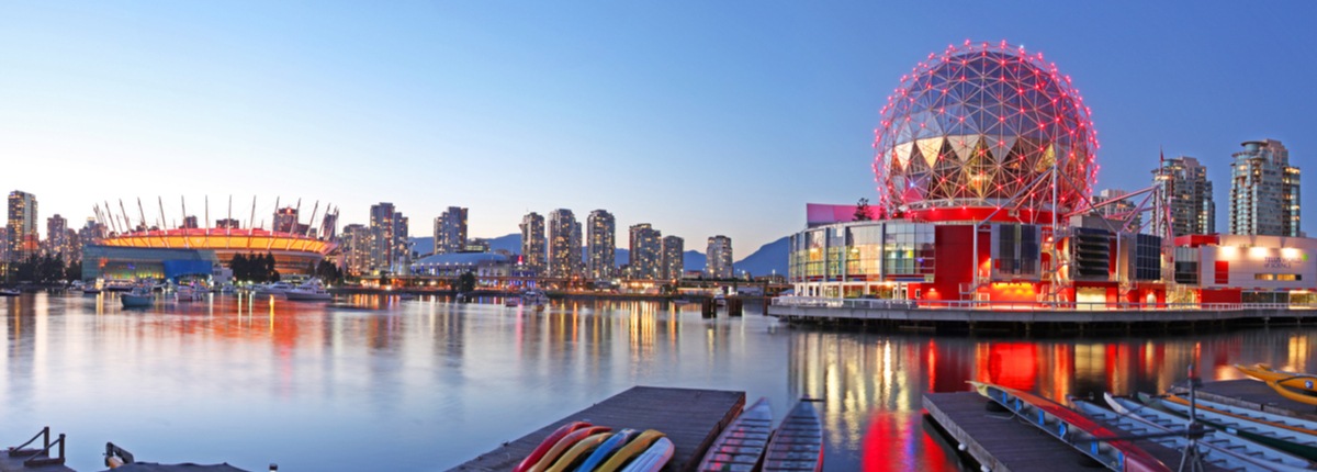 A stadum and a red-lit steel dome stand out in a waterfront cityscape in Vancouver, Canada