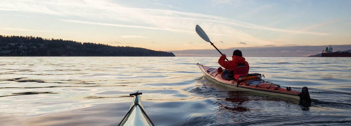 A kayaker paddles across a still lake